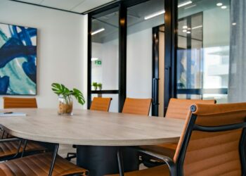 Moderne vergaderruimte met leren stoelen, houten tafel en glazen wanden die zorgen voor licht en transparantie.